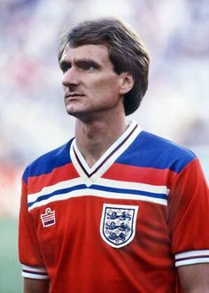 an england soccer player in red and blue jersey looking off to the side with his head tilted