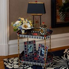 a black and white table with flowers on it in front of a mirror next to a lamp