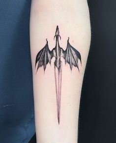 a black and white photo of a bat tattoo on the right arm, with an arrow in the middle