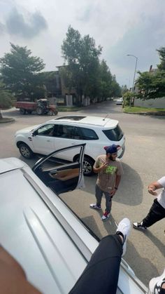 two men standing in front of a white car