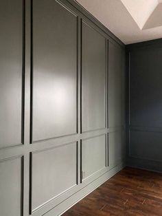 an empty room with gray walls and wood floors