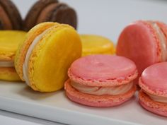 some pink and yellow macaroons are on a white plate