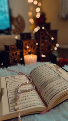 an open book sitting on top of a fluffy white blanket next to a christmas tree