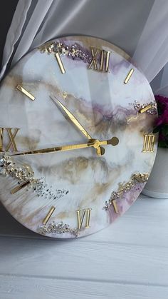 a marble clock with gold numbers and roman numerals sits on a white table