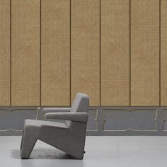 a grey chair sitting in front of a wall with bamboo panels on the walls behind it