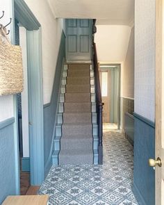 a hallway with blue walls and carpeted stairs leading up to the second floor area