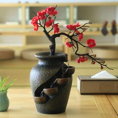 a bonsai tree with red flowers in a vase on a table next to a book