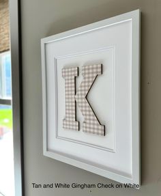 the letter k is cut out of paper and hung on a wall in front of a window