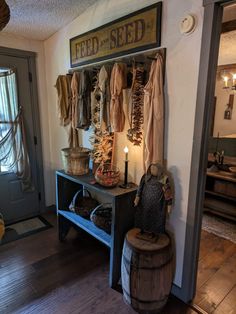 a wooden bench sitting in front of a wall filled with hanging clothes and baskets next to a candle