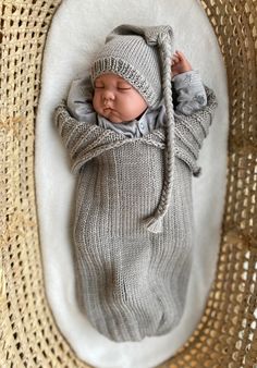 a newborn baby is wrapped in a gray knitted blanket and wearing a grey hat