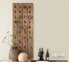 a table with vases and bottles on top of it next to a wall hanging