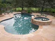 an outdoor swimming pool surrounded by stone patios and seating around the pool is shown