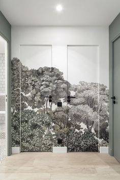 an empty room with trees painted on the wall and two doors leading to another room