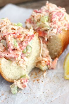 two pieces of bread with crab salad on them next to a lemon and some salt