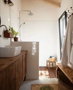 a bathroom with a sink, shower and wooden flooring in front of a window