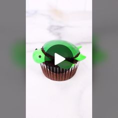 a cupcake with green frosting and a turtle on it's top is shown