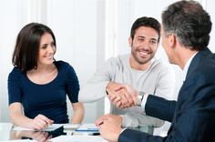 two men and a woman shaking hands in front of a man sitting at a table