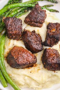 some meat and mashed potatoes on a plate with asparagus