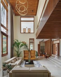 a living room filled with lots of furniture next to tall wooden walls and windows on the ceiling