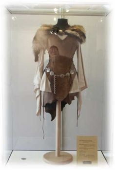 an old fashion dress with fur collars and chains on display in a glass case