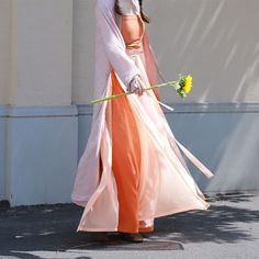 Step into a harmonious blend of history and modern fashion with the colorful Jüzi Qishui 橘子汽水 Orange Soda Changshan & Double Layered Trousers Set! The Changshan 长衫 (long shirt) is made from lightweight and breathable floral jacquard, featuring a contrast trim down the length of the jacket. Elongates the body and adds an extra layer of coverage! Side slits allow the rest of the outfit to peek through and adds ventilation, perfect for even the warmest of days. The Song Ku 宋裤 (Song Dynasty trousers Long Kimono For Festivals, Long Sleeve Orange Kimono For Spring, Traditional Long Kimono For Spring, Festive Orange Set With Sheer Dupatta, Traditional Kimono For Spring Tea Ceremony, Multicolor Spring Wedding Kimono, Traditional Spring Wedding Kimono, Traditional Pink Kimono For Spring, Dunhuang Hanfu