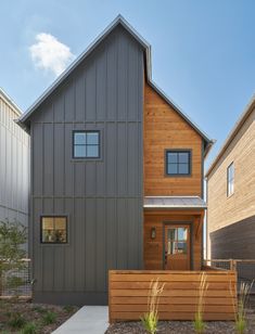 a modern house with wood siding and windows on the front, along side a sidewalk