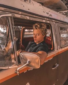 a man sitting in the driver's seat of an old van looking out the window