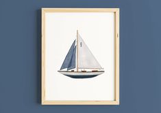 a white and blue sailboat floating in the water on a blue wall with a wooden frame