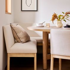 a dining room table with two chairs and a vase on the table next to it