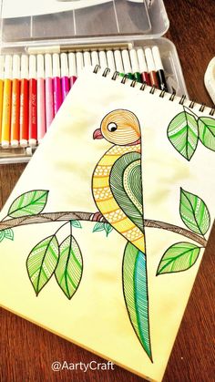 a drawing of a bird sitting on a tree branch with leaves and crayons next to it