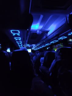 the interior of a bus is lit up with blue lights and people are sitting in seats