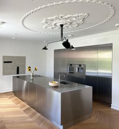 a modern kitchen with stainless steel appliances and wood flooring in the middle of the room