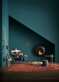 a living room with a chair, ladder and fire place in the corner that is painted teal