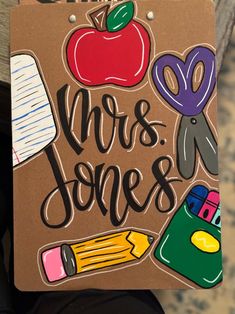 a sign that says mrs jones with an apple and pencils on it's side