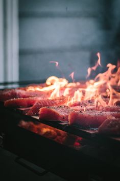 some meat is cooking on a grill with flames