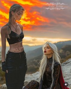 two beautiful young women sitting on top of a rocky hill next to each other with the sun in the background