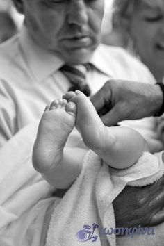 a black and white photo of a baby being held by an older man who is wearing a tie