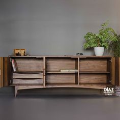 the sideboard is made out of wood and has two plants on top of it