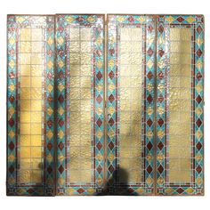 three paneled stained glass screen with gold and blue designs on the sides, in front of a white background