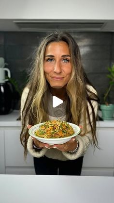 a woman is holding a bowl of food in her hands and looking at the camera