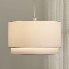 a white lamp hanging from a ceiling with curtains in the background