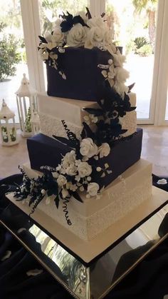 a three tiered wedding cake with white flowers on the side and black ribbon at the top