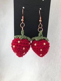 two crocheted strawberries hanging from hooks on a black hook - earring