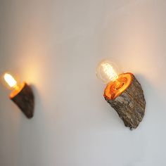 two light bulbs are on the wall next to a piece of wood that has been carved into it