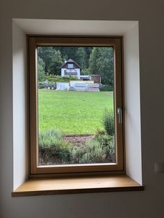 an open window with a view of a green field and a house in the distance