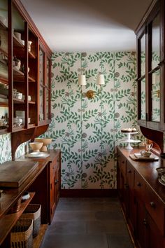 a kitchen with wooden cabinets and green wallpaper on the walls, along with an old fashioned sink