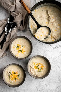 four bowls filled with soup sitting on top of a counter next to two spoons