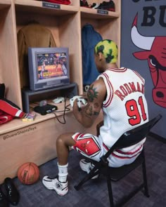 a toy basketball player sitting in front of a tv set with his foot on the chair