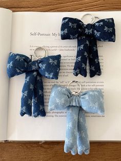 four blue bows are on top of an open book with two keychains attached to them