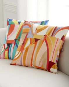 three colorful pillows sitting on top of a white couch